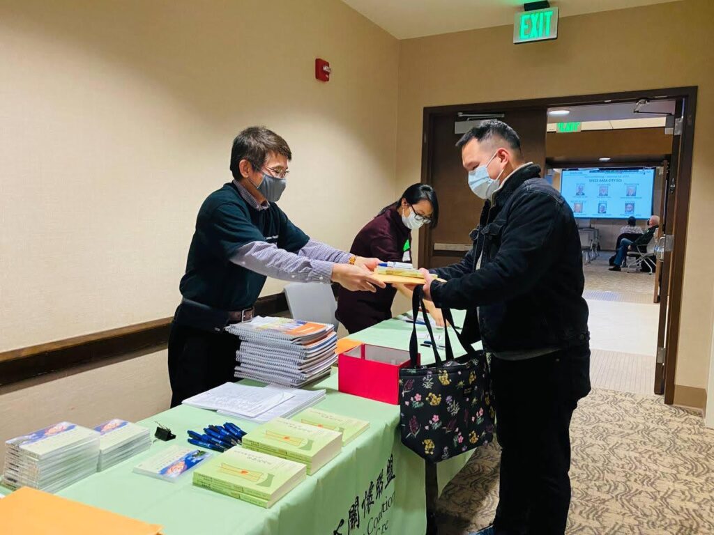 CACCC volunteer courteously handing materials to attendee